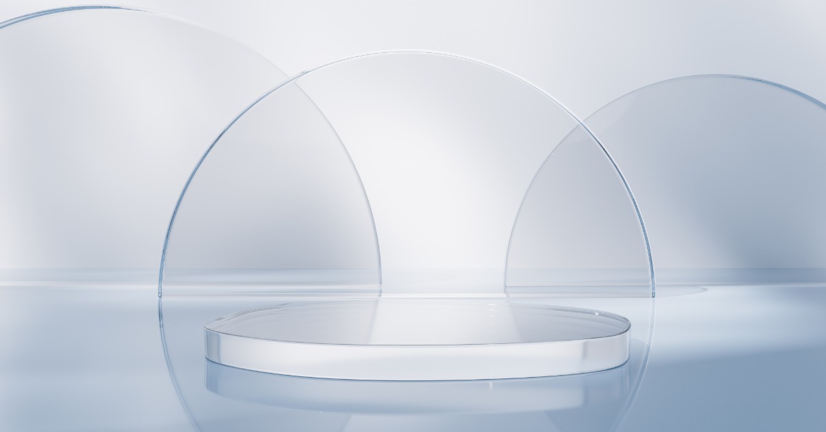 Transparent circular glass discs arranged upright around a flat glass lens on a reflective white surface.